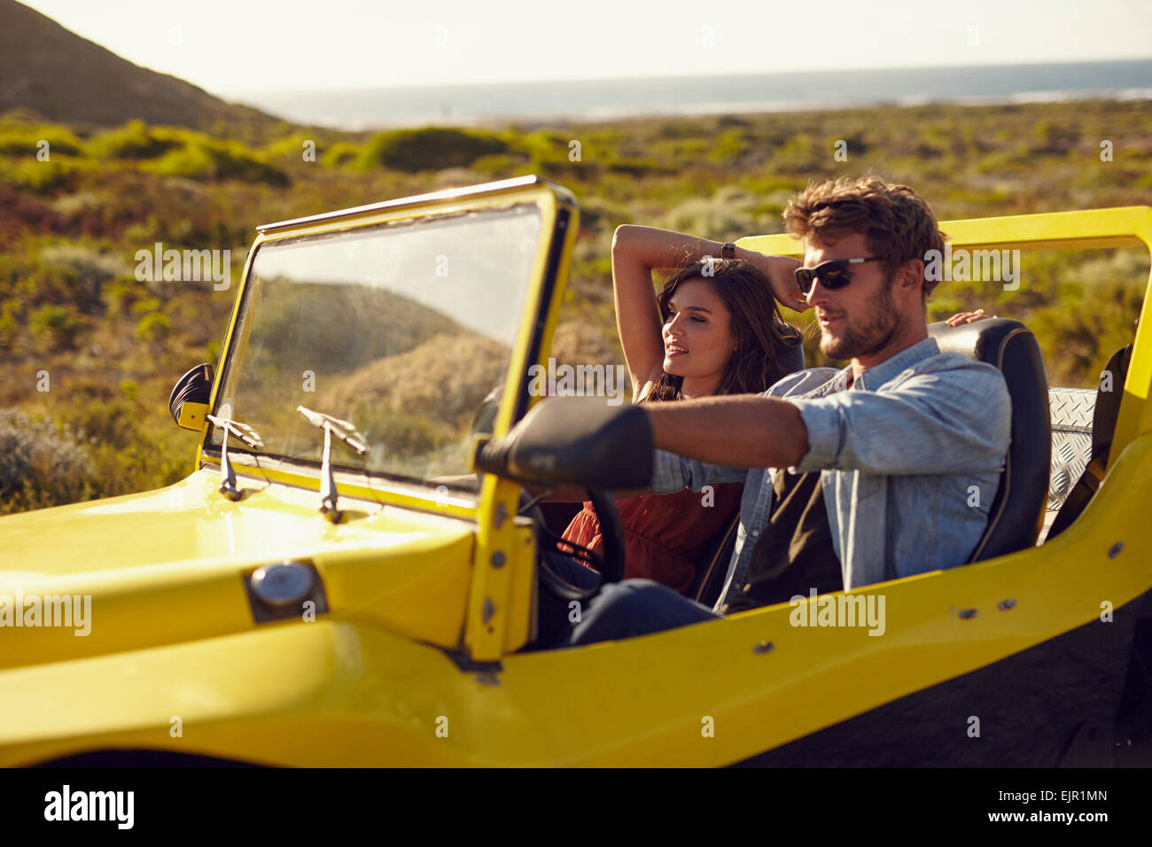 Young couple driving their car on a roadtrip. Handsome young man with his girlfriend on a holiday. Couple on a long drive. Stock Photo