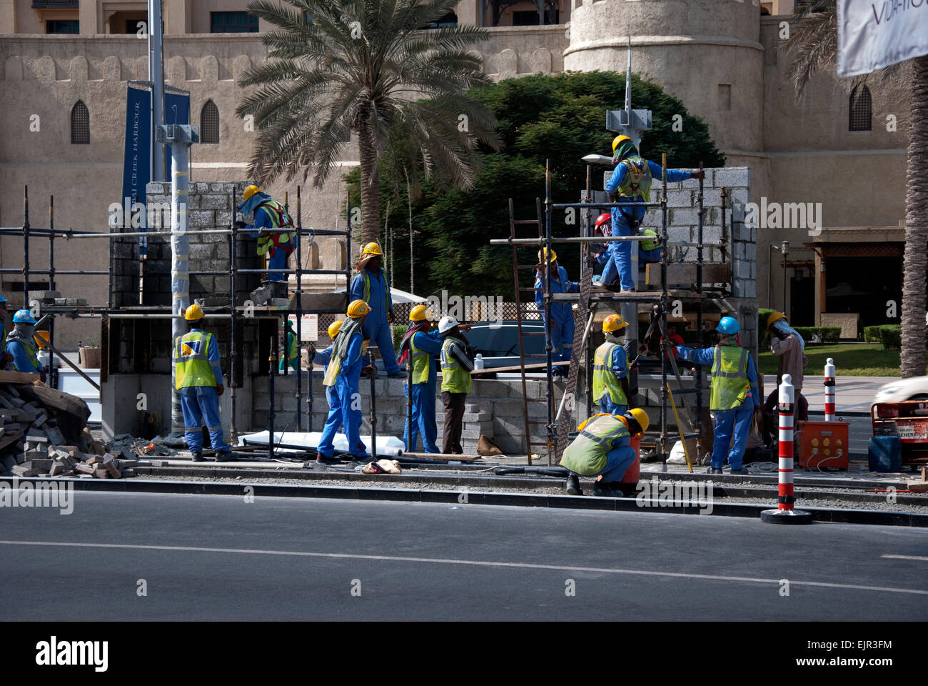 Squad of Migrant Workers Constructing Trolley Bus Stop Stock Photo