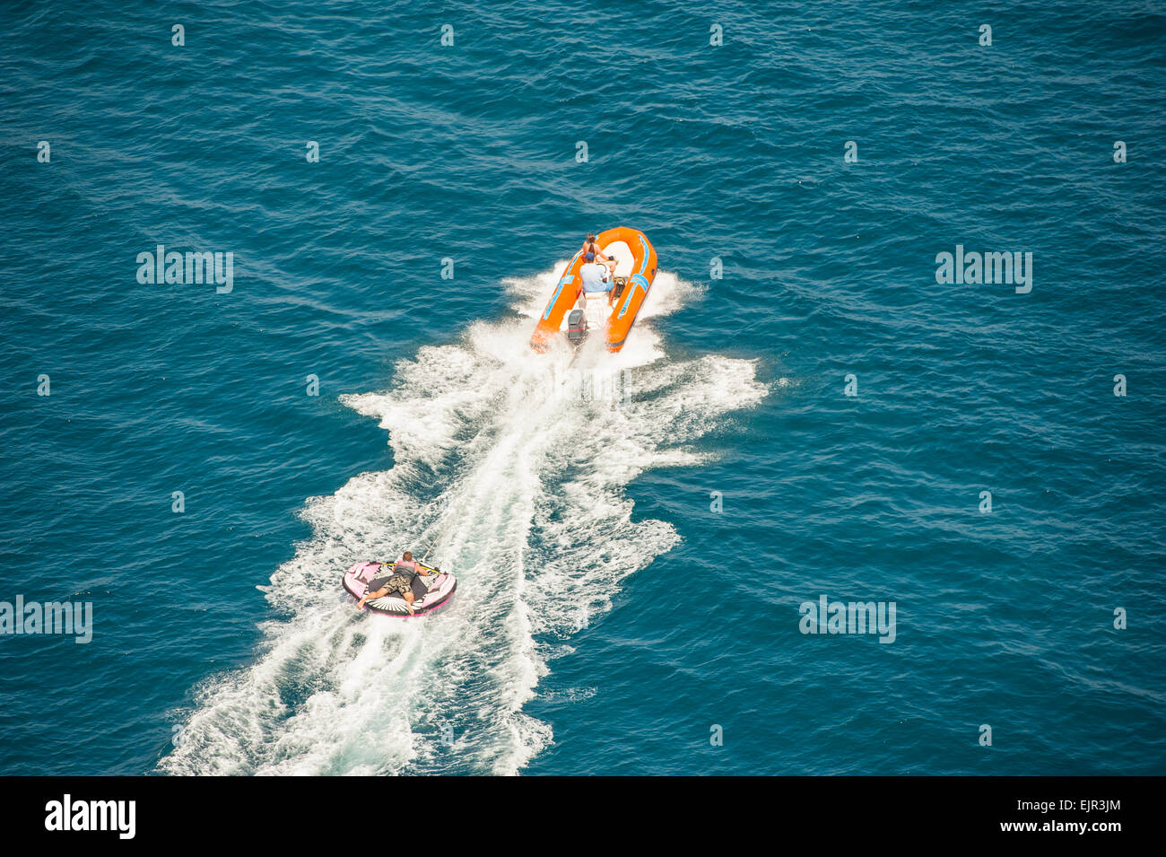 Inflatable toy being towed behind a speed boat during summer tropical sea holiday vacation Stock Photo