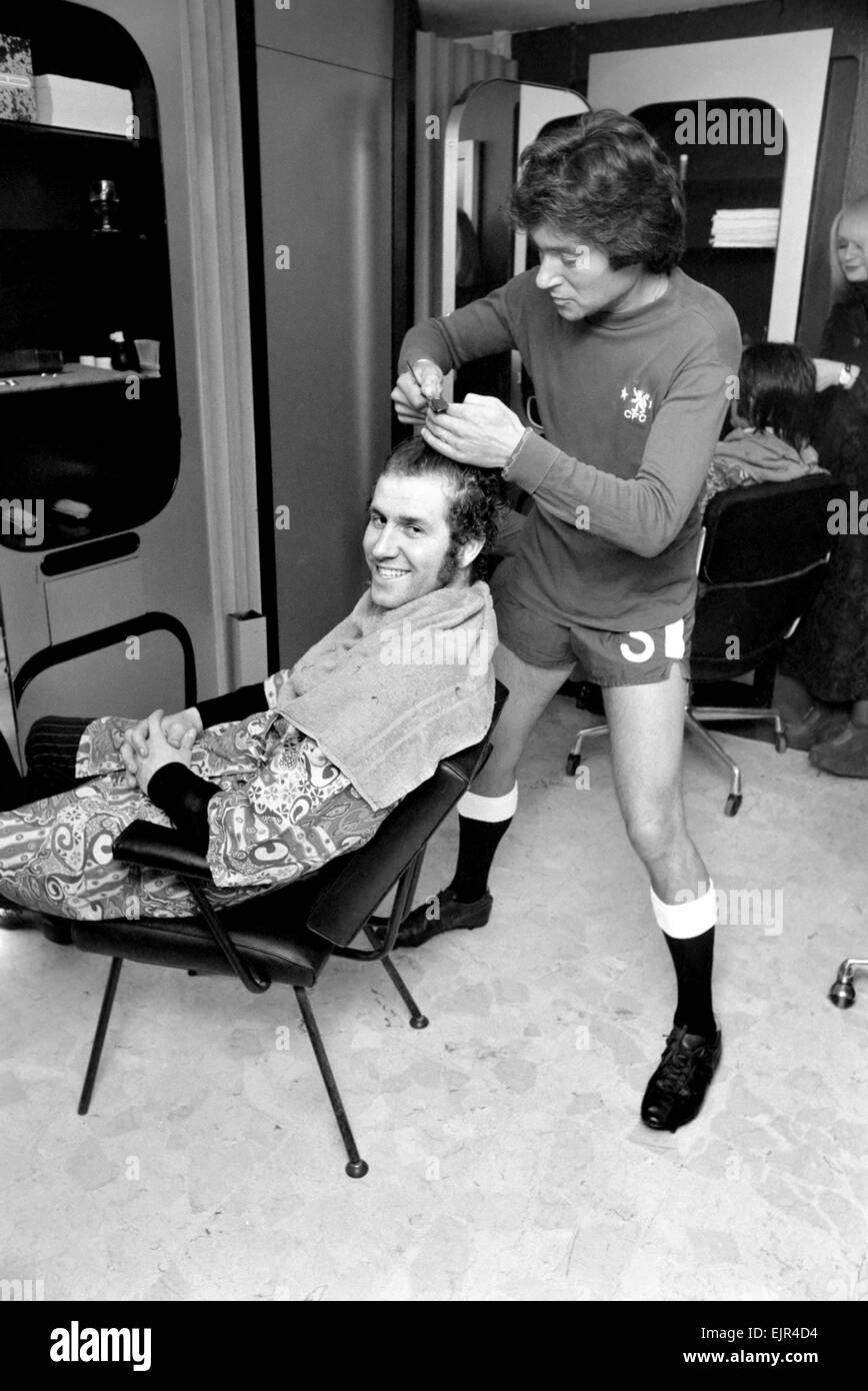 Football fan Vidal Sassoon made a solemn promise that if Chelsea reached the final of the Football League Cup the players and their wives would all get a free hair-do for the occasion. Chelsea are in the Final and Vidal kept this promise. Vidal Sassoon's dressed in Chelsea's Football strip and seen cutting the hair of England and Chelsea's Centre Forward Peter Osgood. March 1972 72-2010-009 Stock Photo