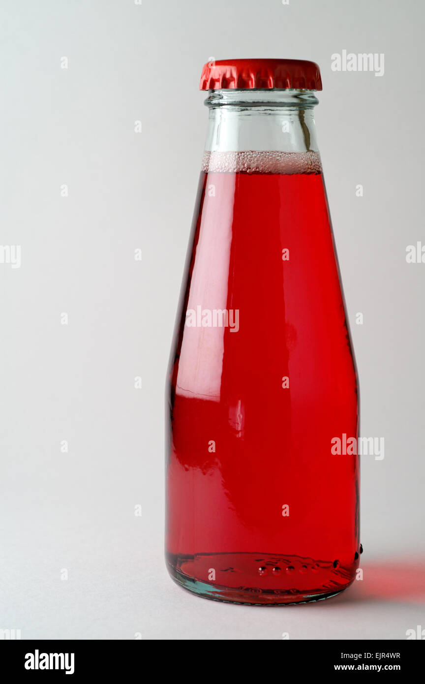 Red drink with bubbles in bottle closed with red crown cap Stock Photo