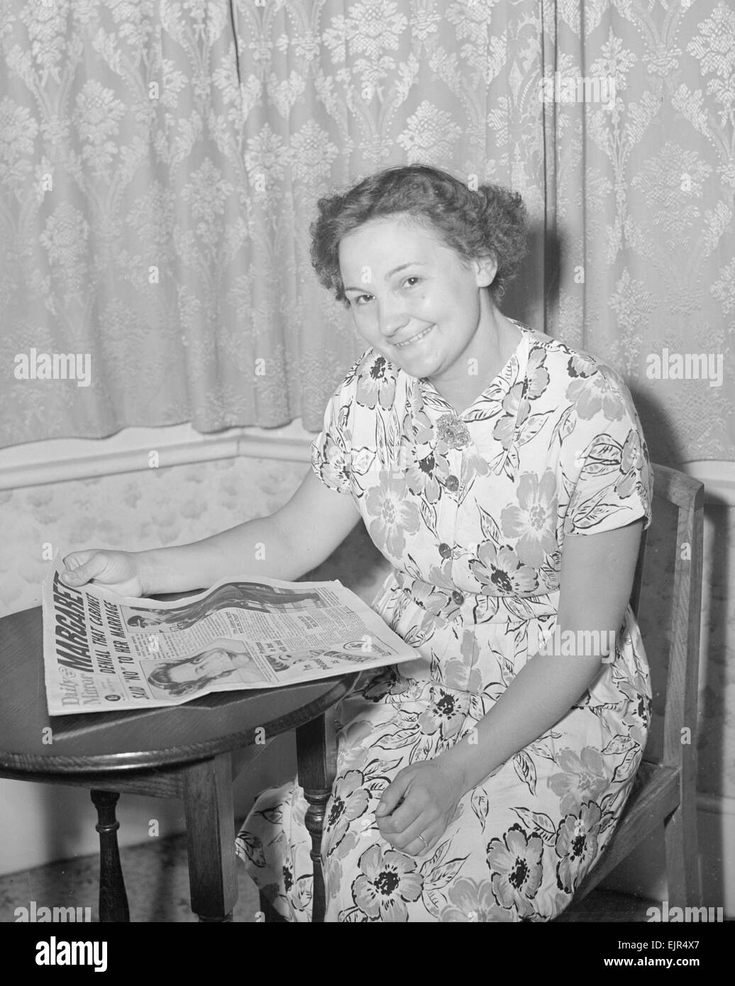 Mrs Higgins seen here reading about Princess Margaret and Peter Townsend in the Daily Mirror. 13th July 1953 Stock Photo