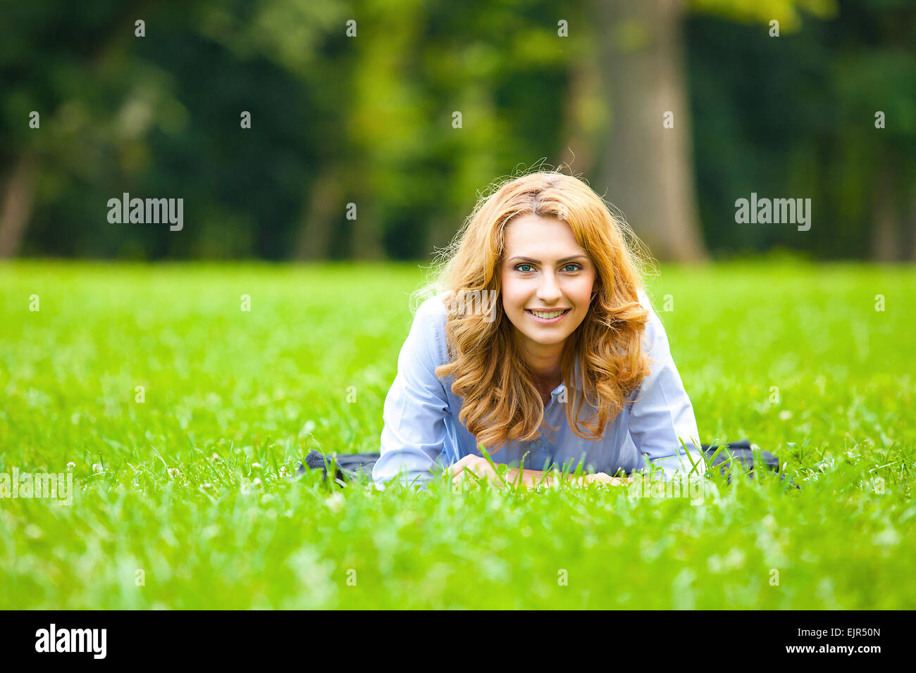beautiful young woman lying in green grass with happy mood Stock Photo