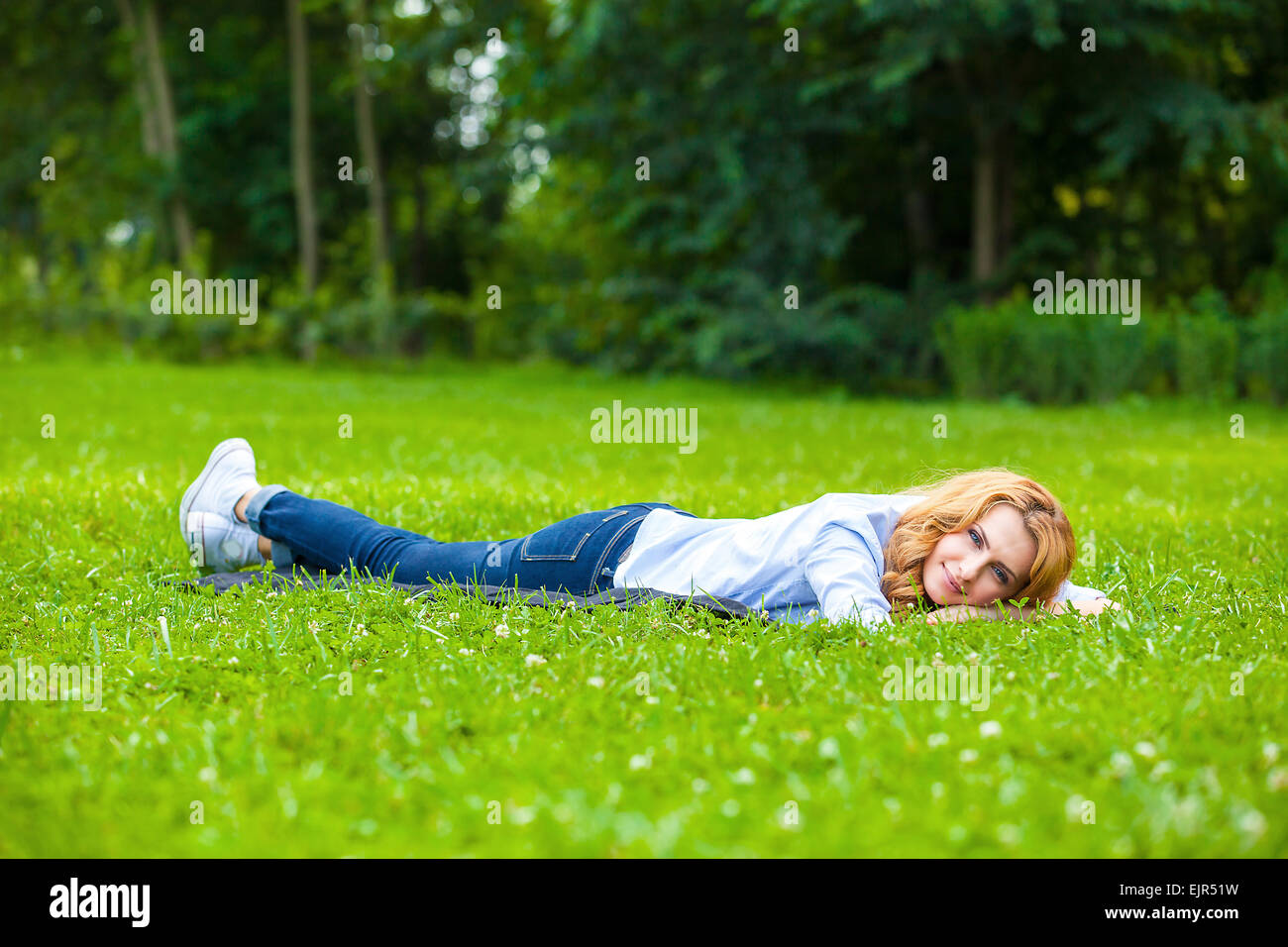 young blonde woman relaxing in park on green grass Stock Photo - Alamy