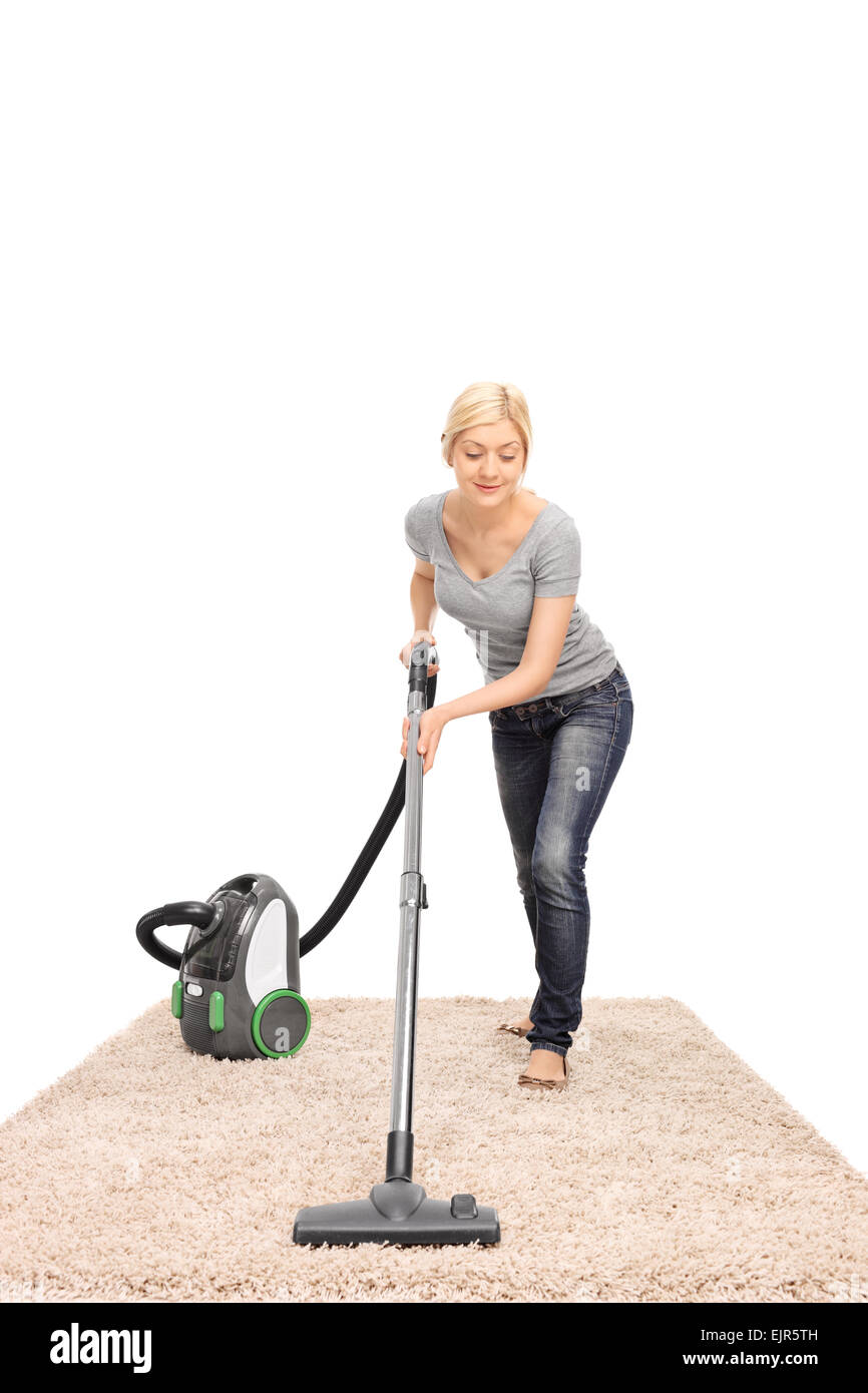 Full length frontal view of a young housewife vacuuming a beige colored carpet isolated on white background Stock Photo