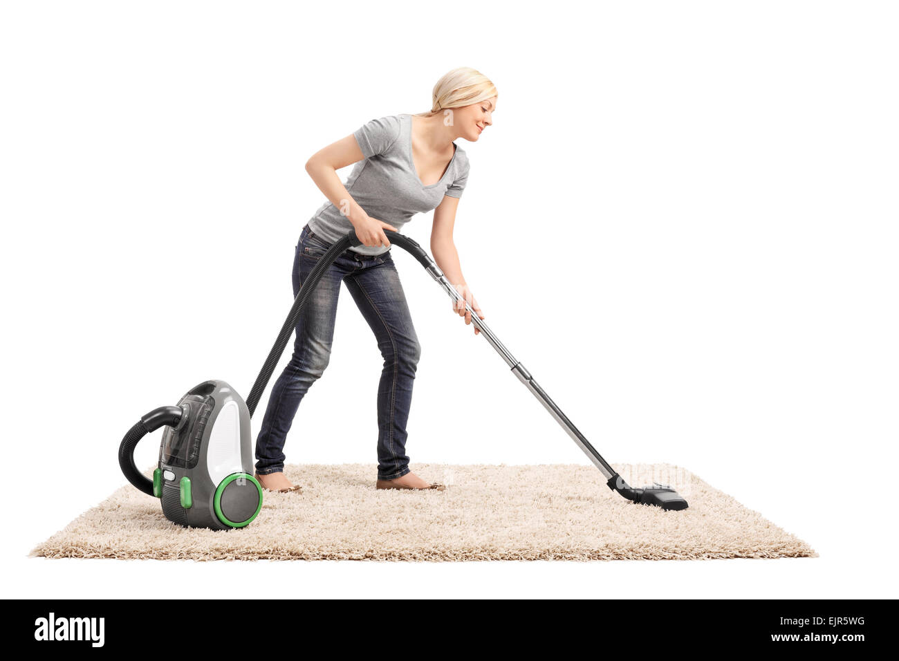 Full length portrait of a woman vacuuming a beige colored carpet with a vacuum cleaner isolated on white background Stock Photo