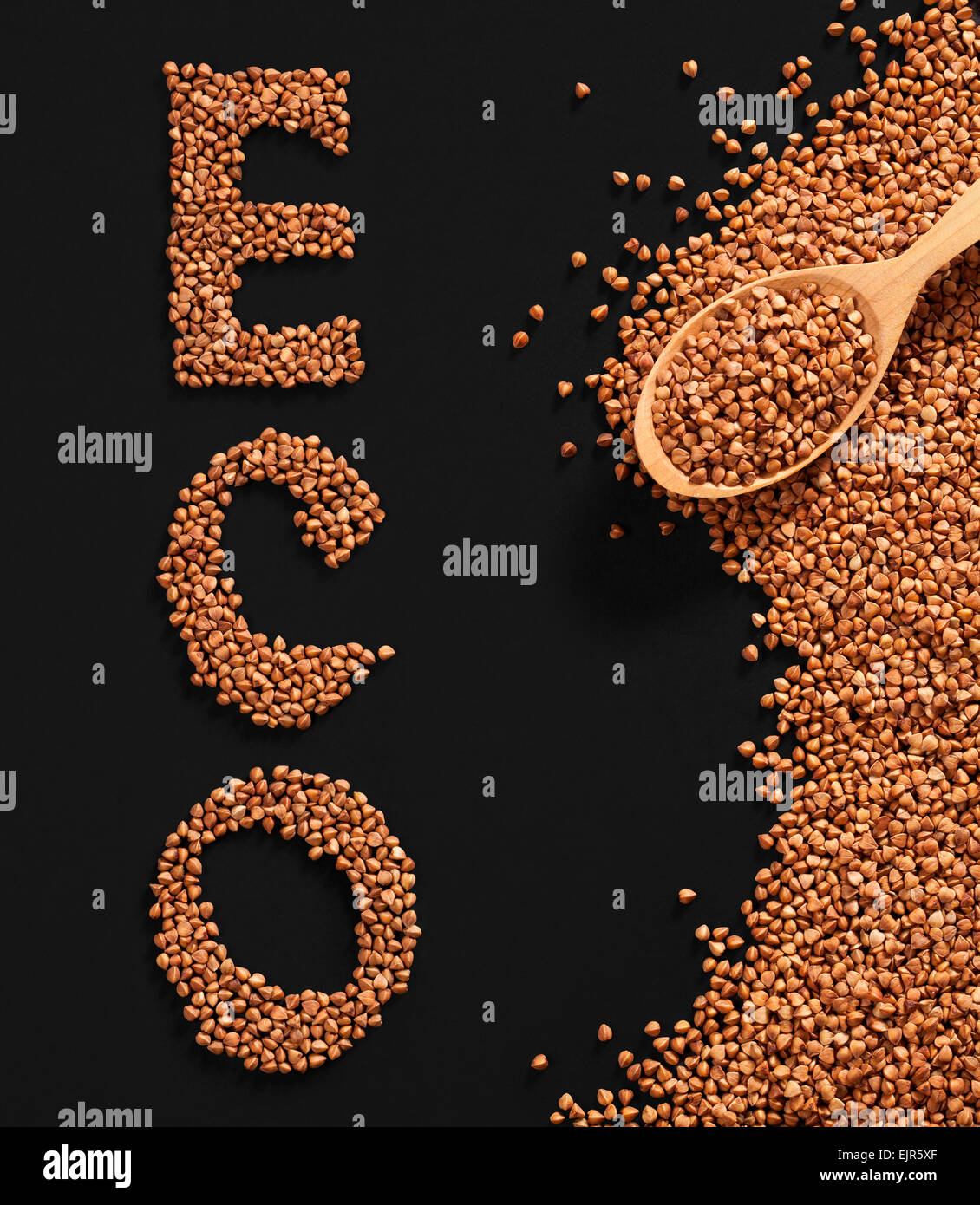Word ECO composed of premium buckwheat groats on black background with wooden spoon Stock Photo