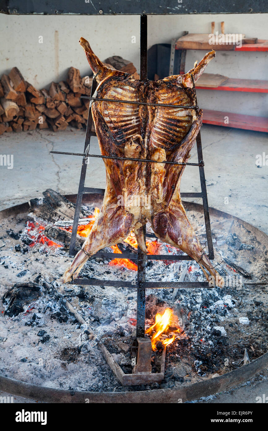 Chilean traditional Asado lamb cooking in iron support Stock Photo