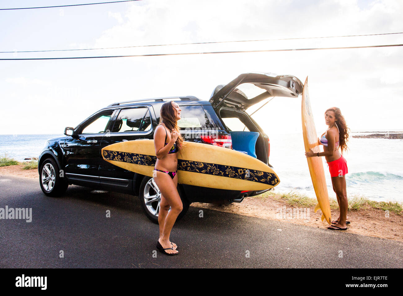 Surfers unloading surfboards from car near beach Stock Photo