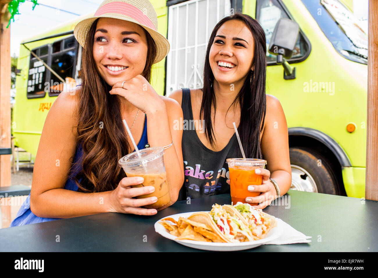 Pacific Islander women eating and drinking near food cart Stock Photo