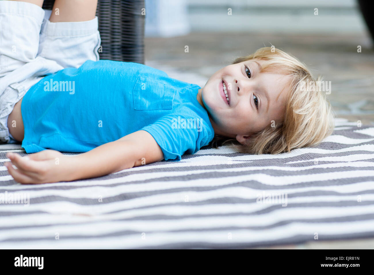 Smiling Caucasian boy laying on rug Stock Photo - Alamy