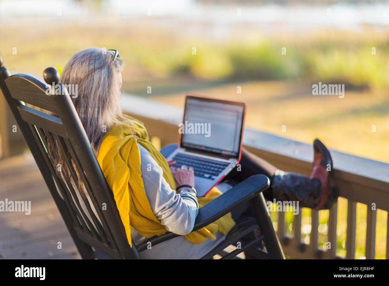 Older Caucasian woman using laptop on porch Stock Photo