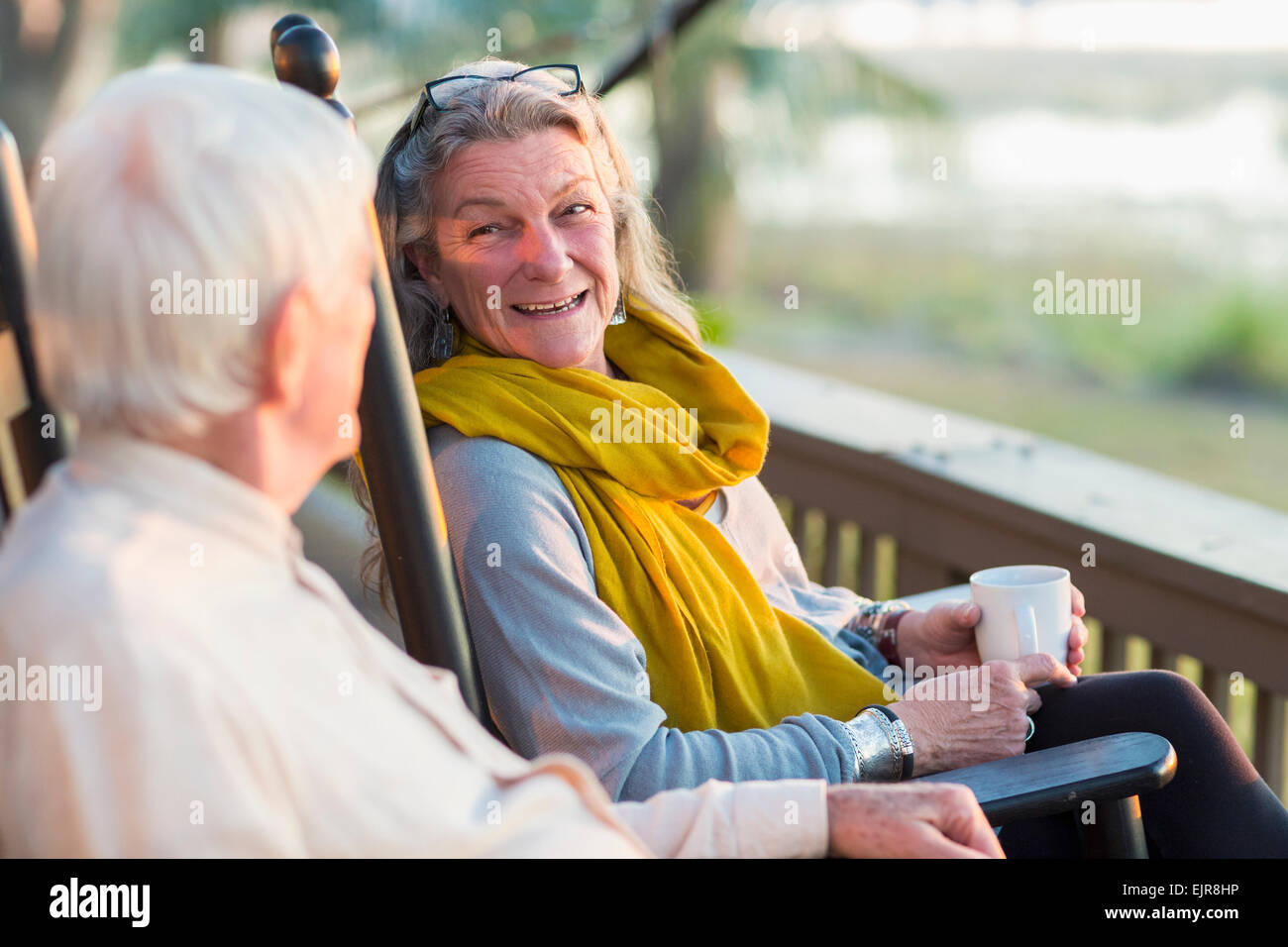 Older Caucasian couple drinking coffee on porch Stock Photo