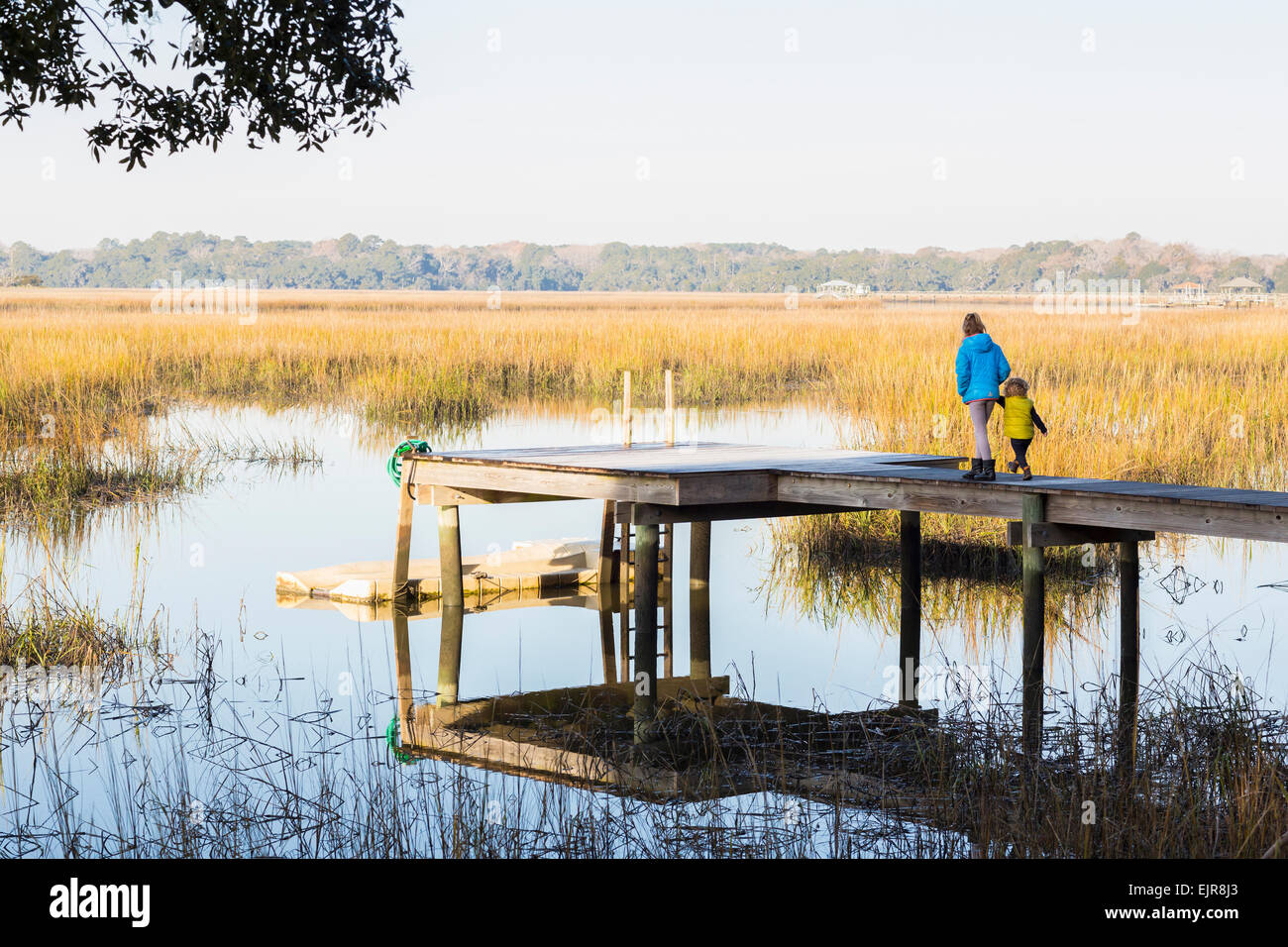 Caucasian children walking on wooden dock over lake Stock Photo