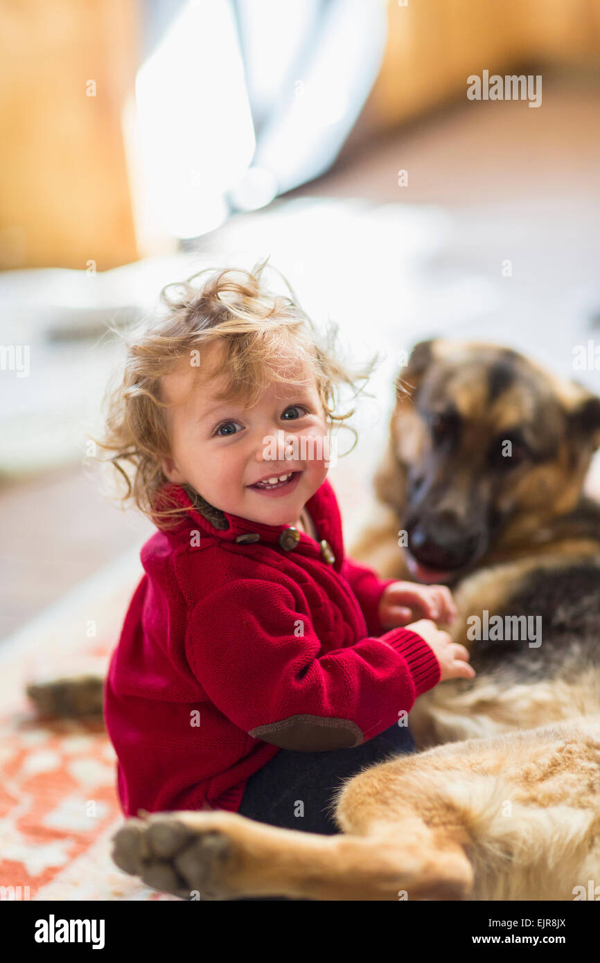 Caucasian baby boy playing with dog on floor Stock Photo