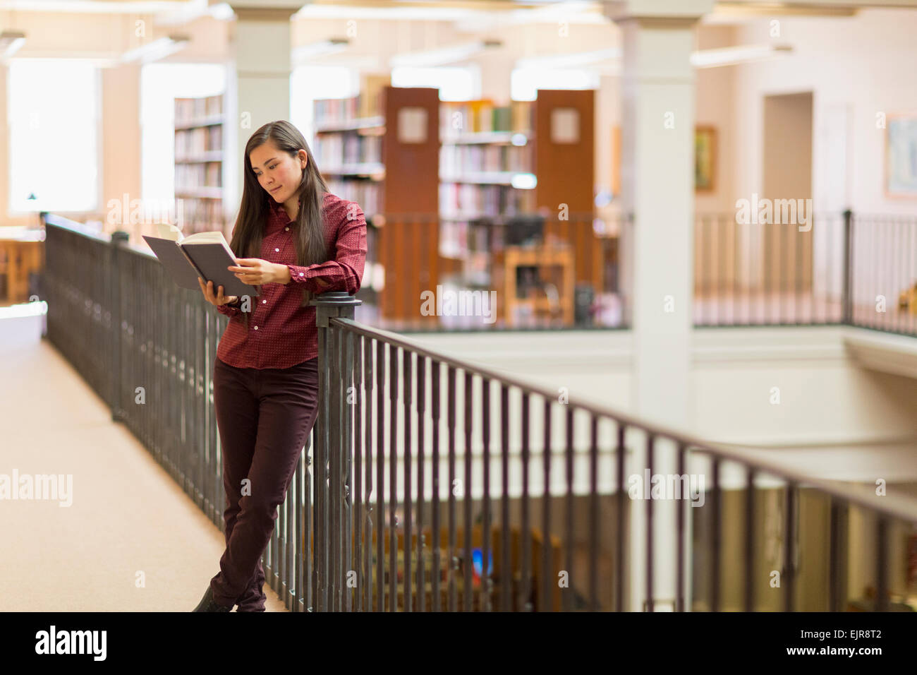 Mixed race student reading in library Stock Photo