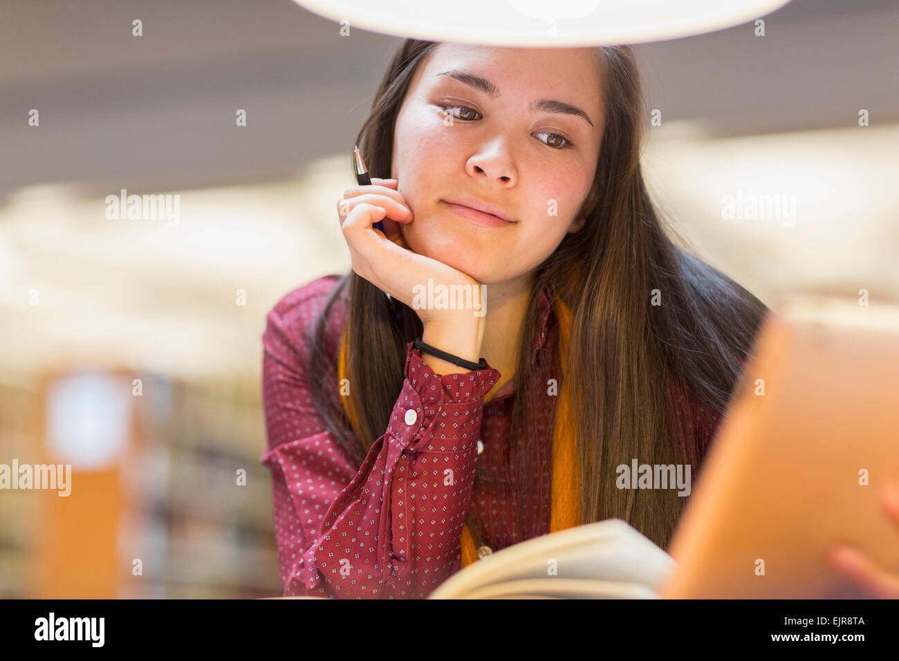 Mixed race student reading in library Stock Photo