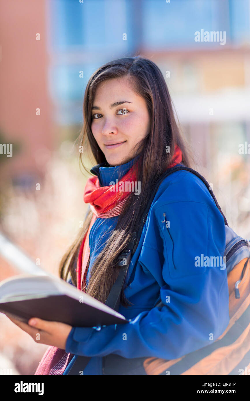 Mixed race student holding books on campus Stock Photo