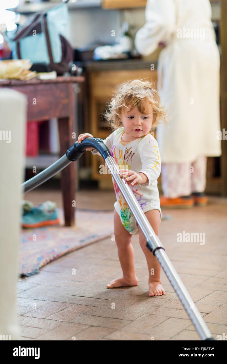 Caucasian baby boy vacuuming in kitchen Stock Photo