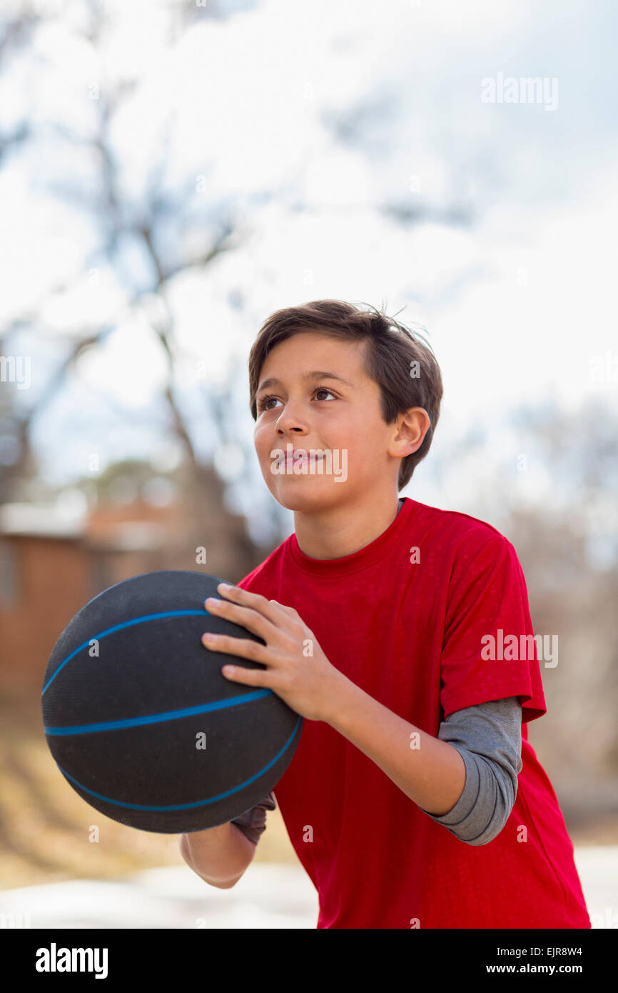 Caucasian boy playing basketball outdoors Stock Photo