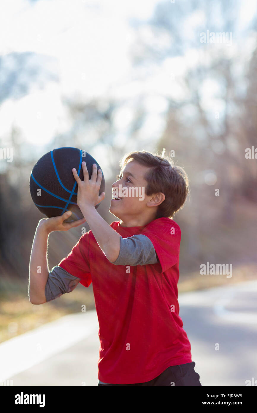 Caucasian boy playing basketball on court Stock Photo