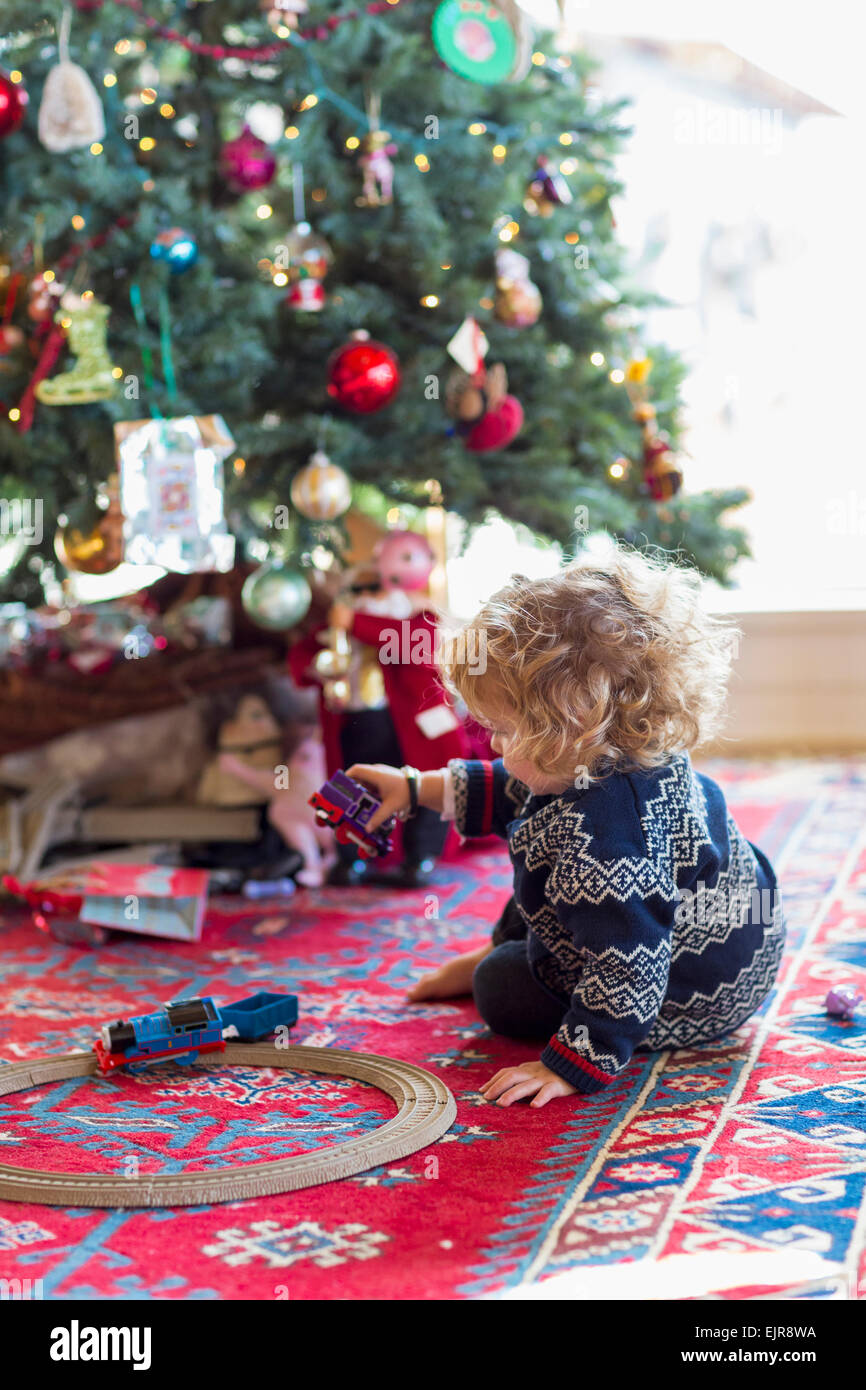 Caucasian baby boy playing with toys under Christmas tree Stock Photo