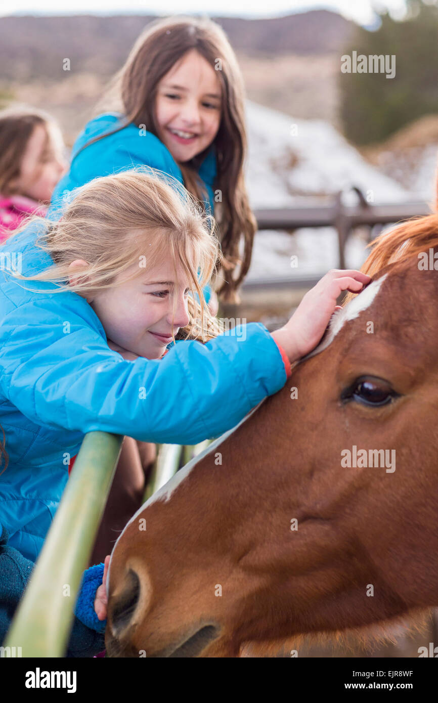 Caucasian girls petting horse on ranch Stock Photo