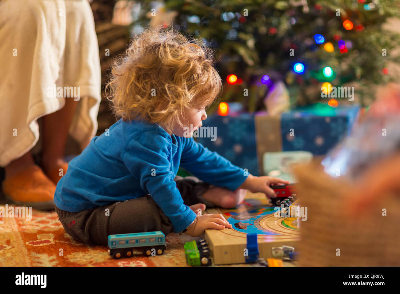 Caucasian baby boy playing with toys under Christmas tree Stock Photo