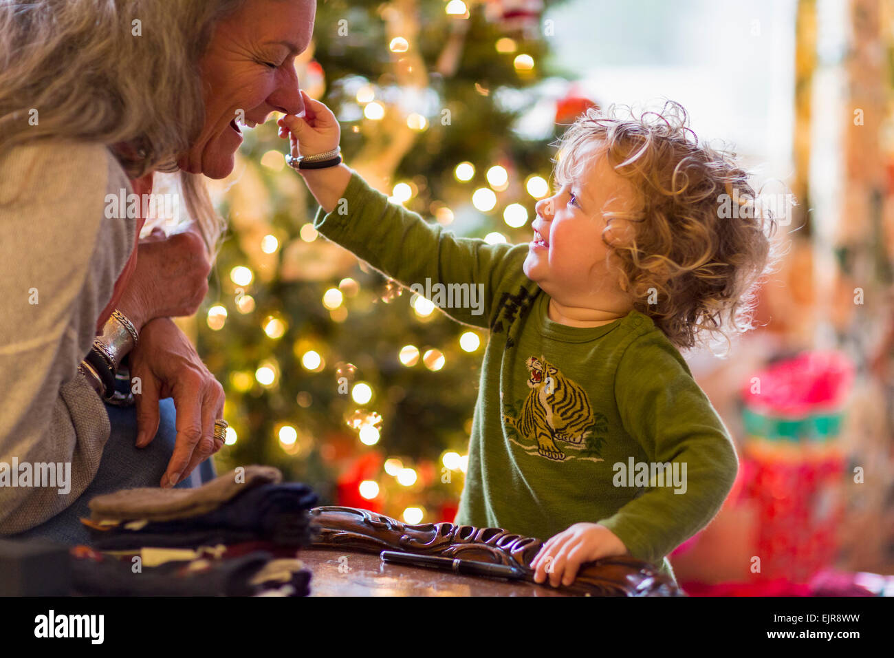 Caucasian grandmother and grandson playing with toys near Christmas tree Stock Photo