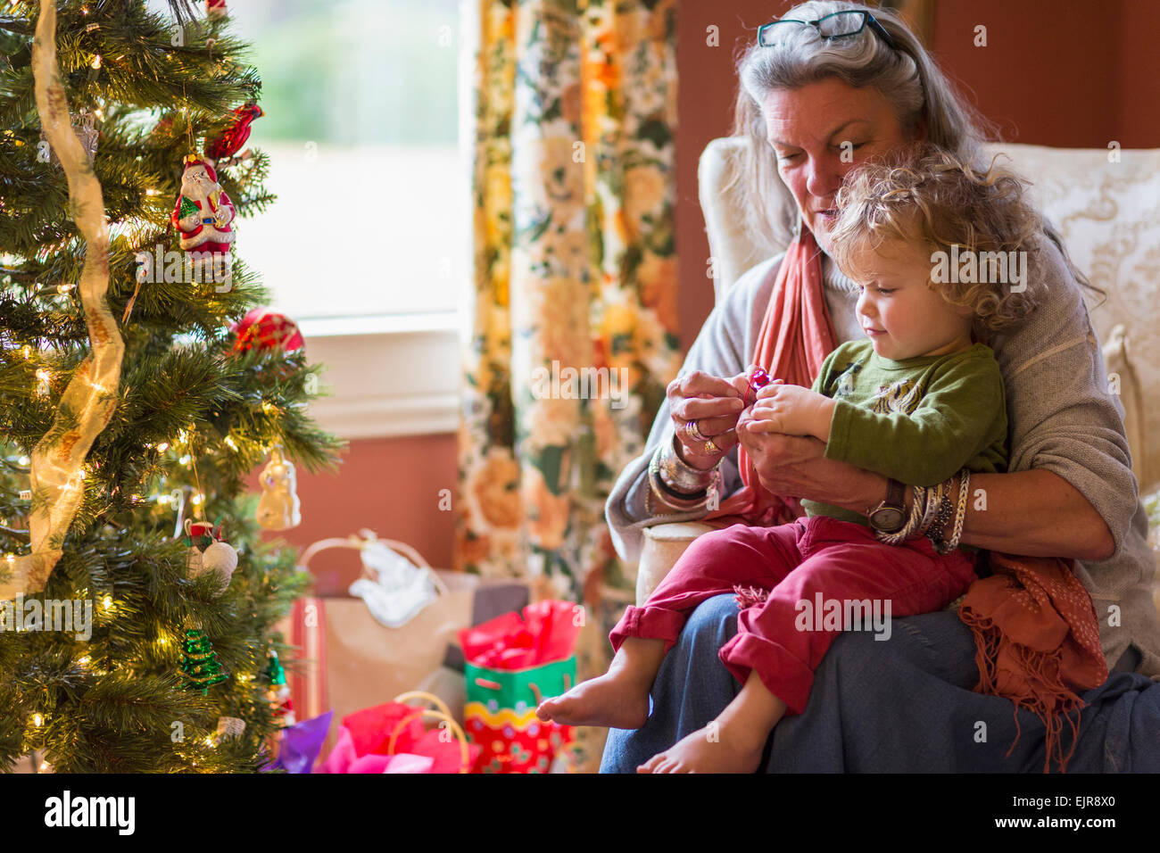 Caucasian grandmother and grandson opening presents near Christmas tree Stock Photo
