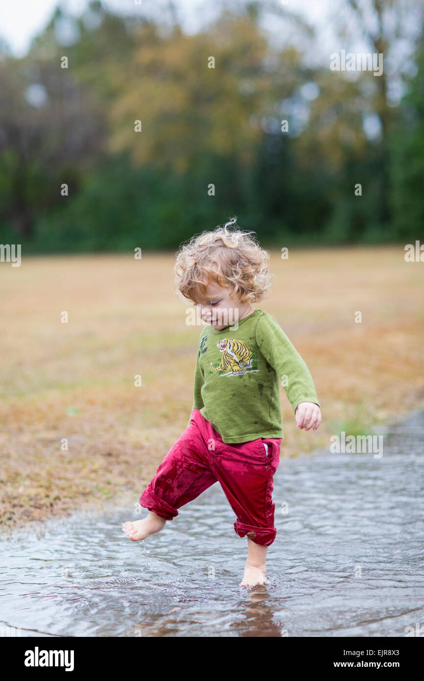 Caucasian baby boy splashing in puddle Stock Photo