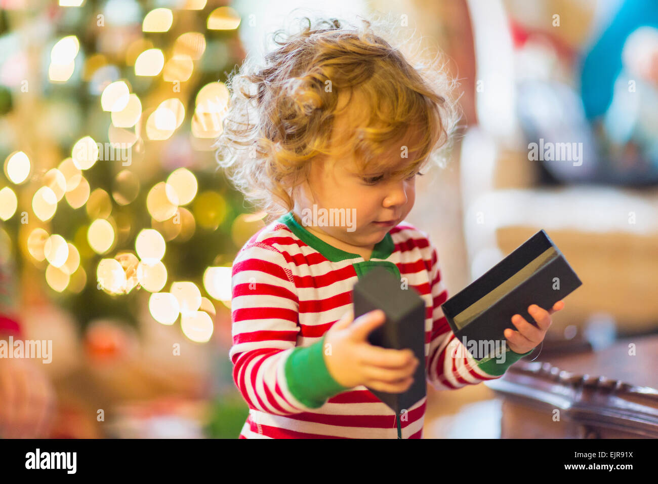 Caucasian baby boy opening present near Christmas tree Stock Photo