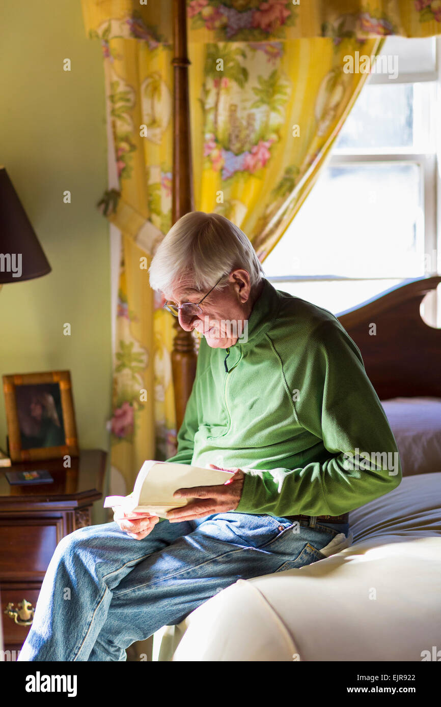 Older Caucasian man reading on bed Stock Photo