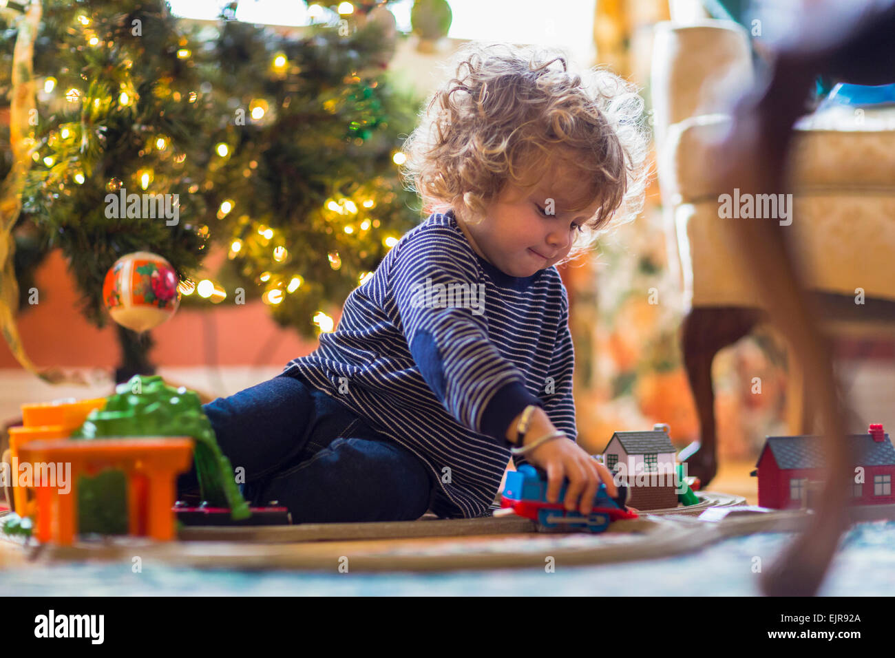 Caucasian baby boy playing with toys near Christmas tree Stock Photo