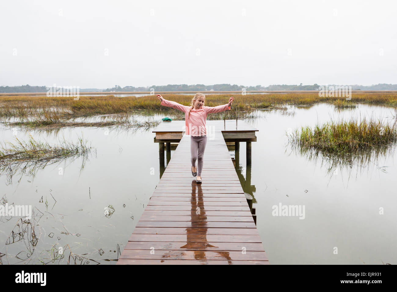 Caucasian girl standing on wooden dock over lake Stock Photo