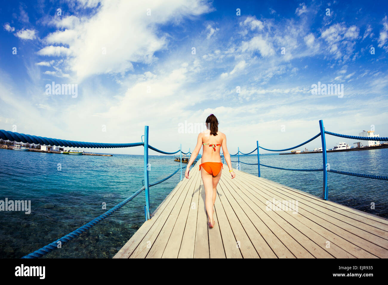 Caucasian girl walking on wooden dock over sea Stock Photo