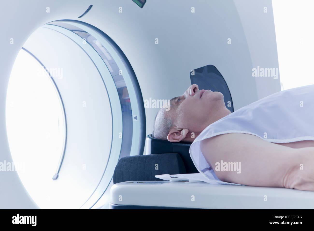 Older Hispanic man laying in MRI scanner Stock Photo