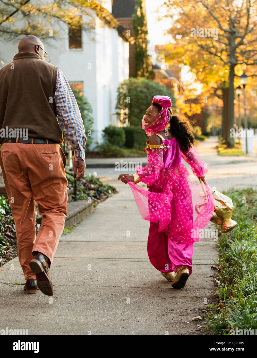 African American girl trick-or-treating with father on Halloween Stock Photo