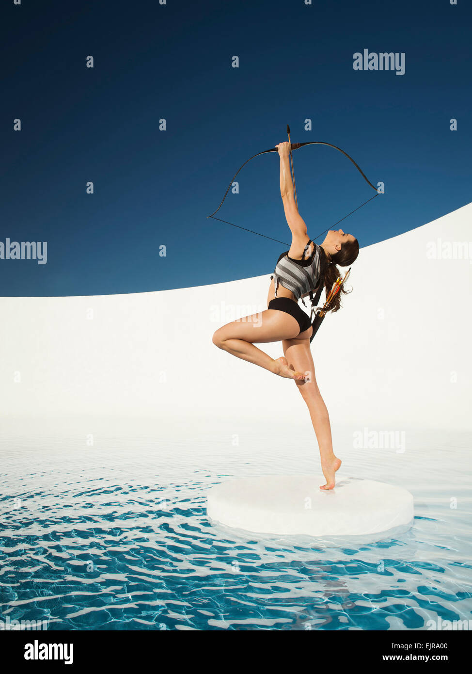 Caucasian woman aiming bow and arrow on ice floe Stock Photo