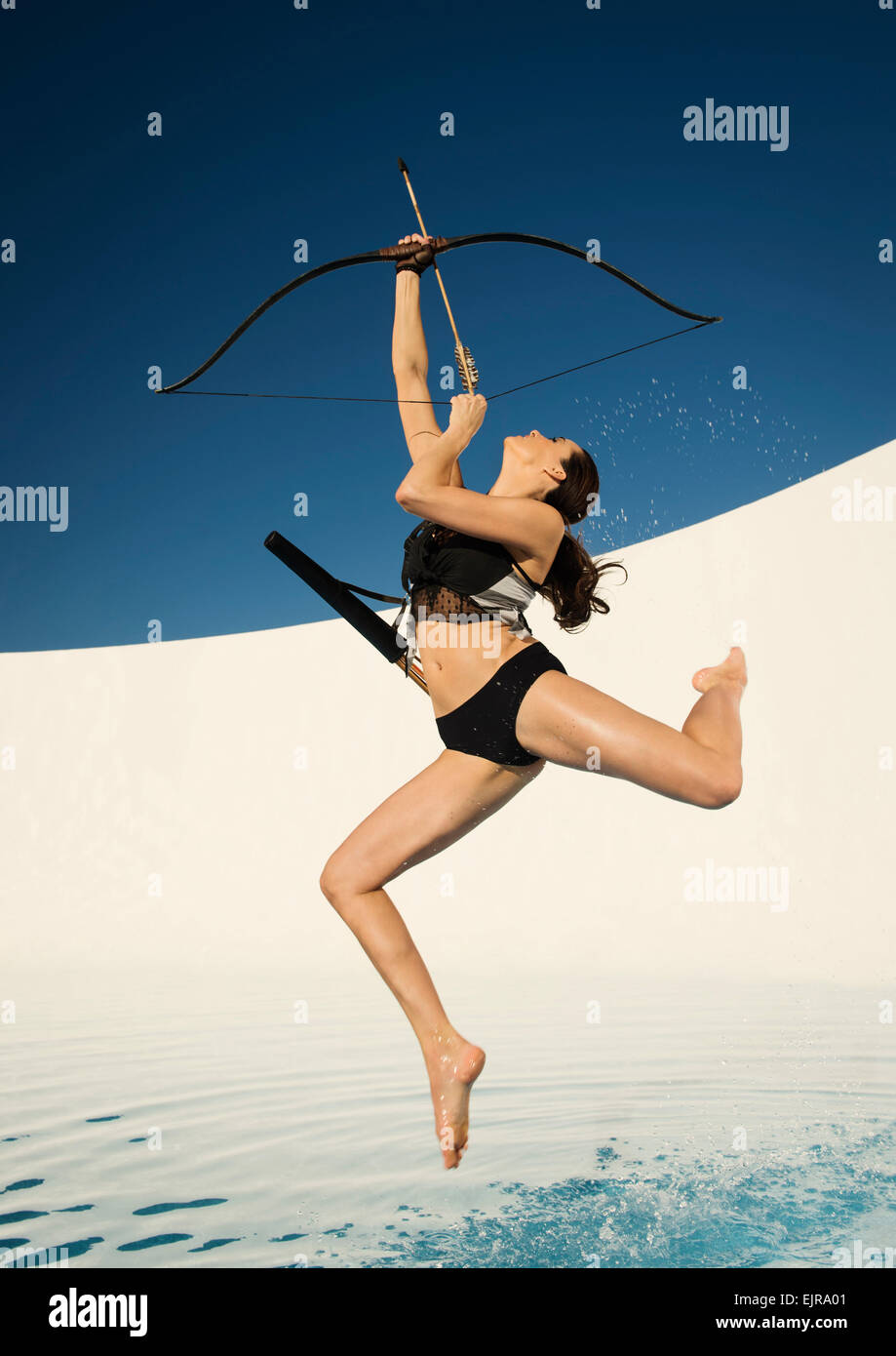 Caucasian woman aiming bow and arrow Stock Photo