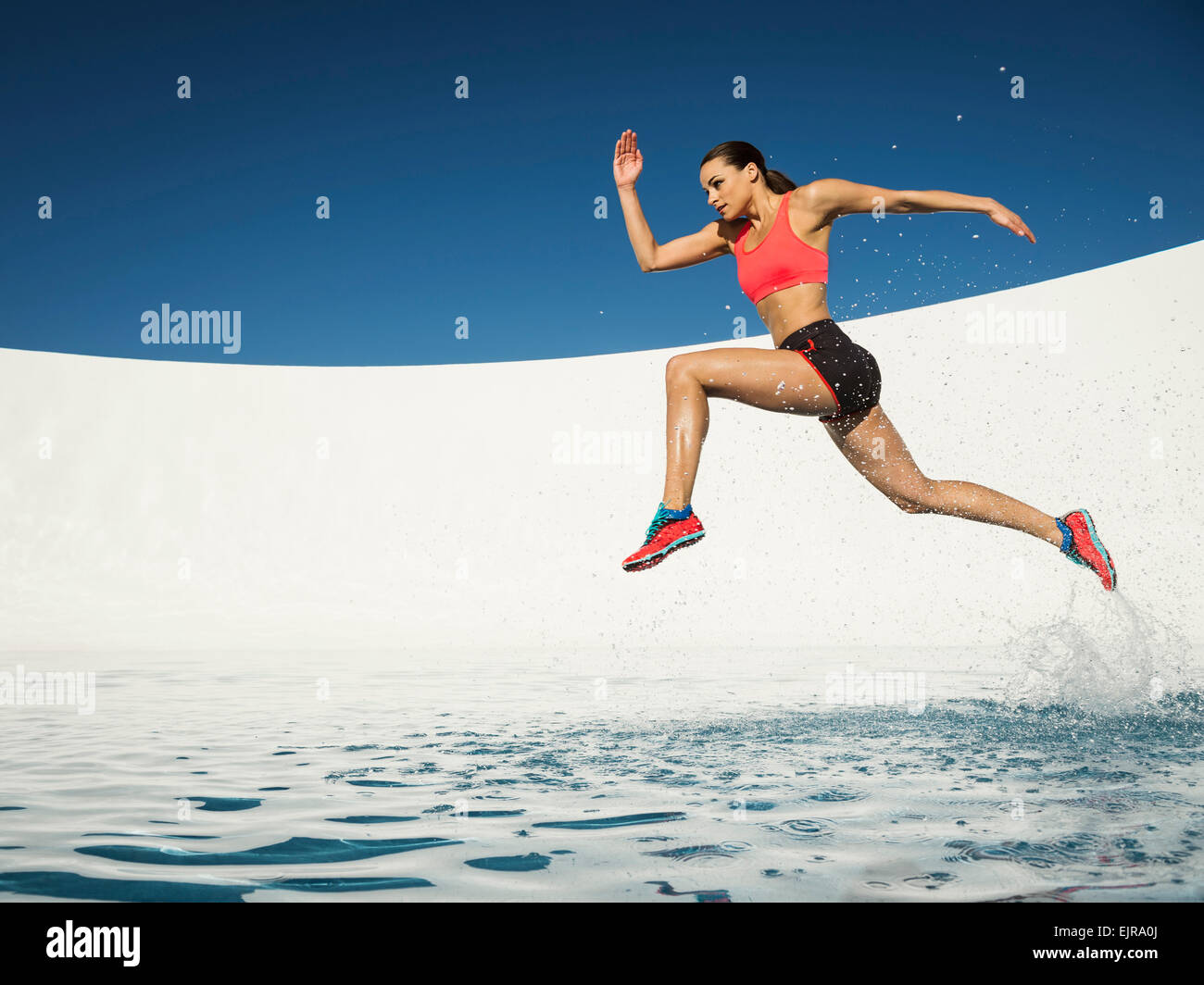 Caucasian woman running on water surface Stock Photo