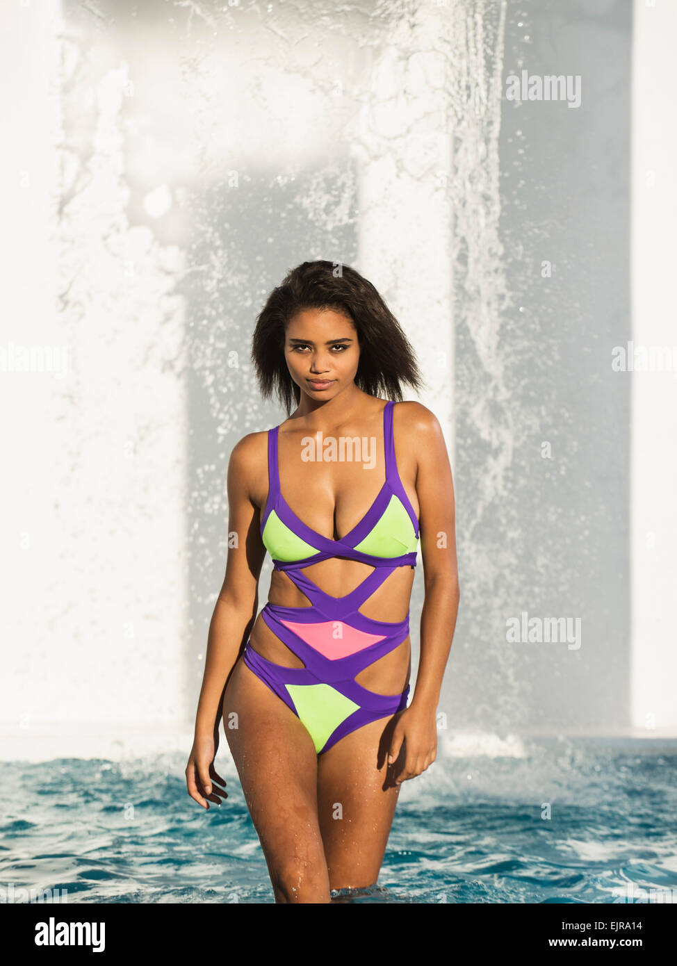 Mixed race woman wearing colorful swimsuit in swimming pool Stock Photo