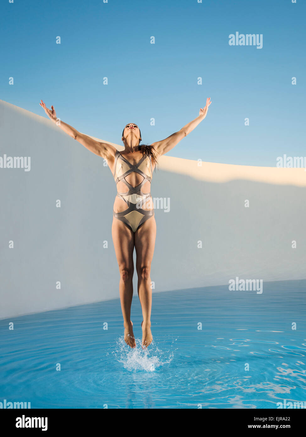 Caucasian woman jumping on swimming pool Stock Photo