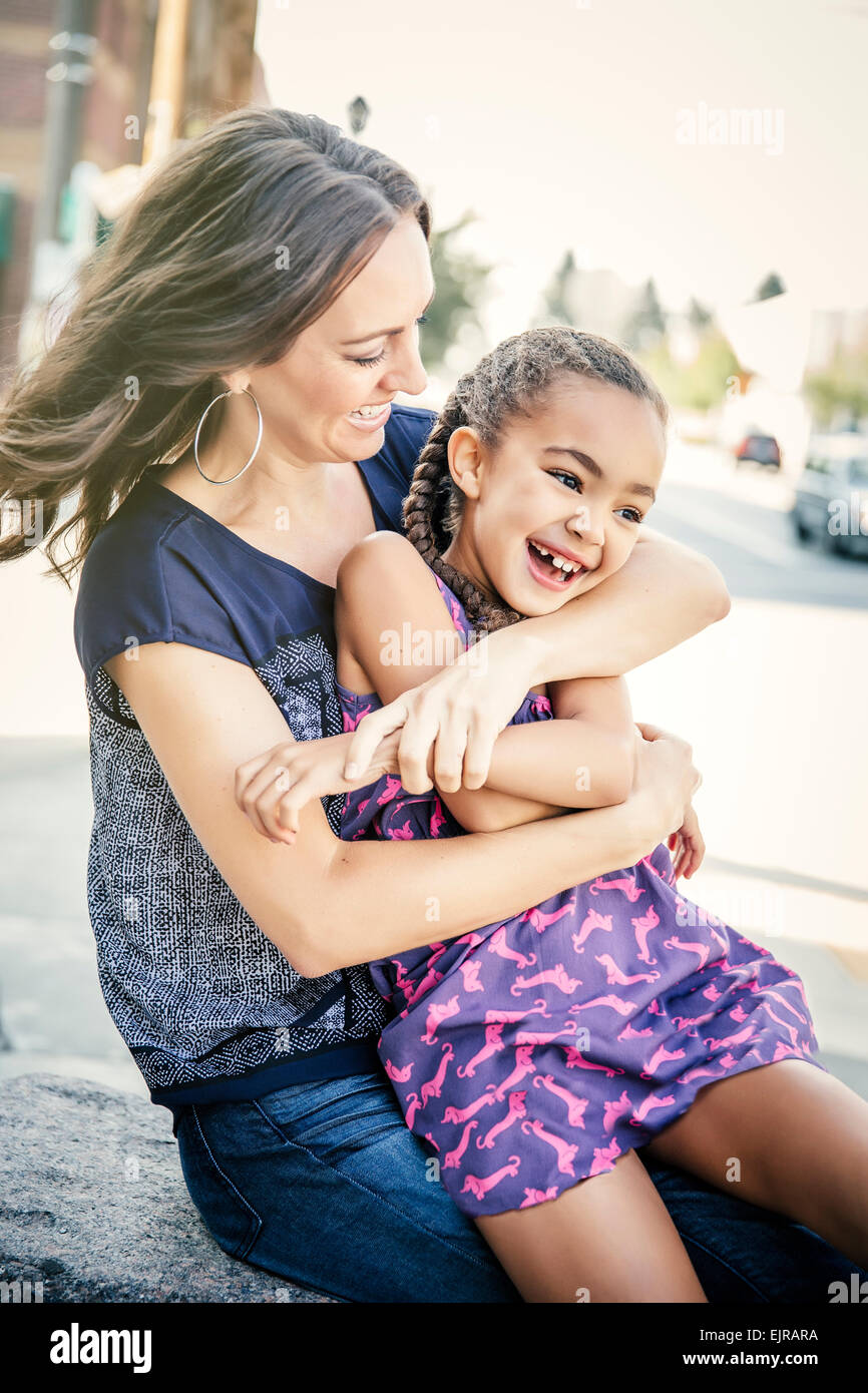 Mother and daughter hugging on sidewalk Stock Photo