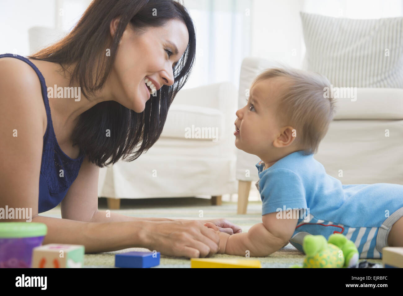 Mixed race mother playing with baby on floor Stock Photo