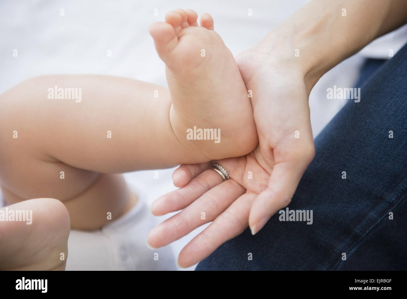 Close up of mixed race mother holding foot of baby Stock Photo