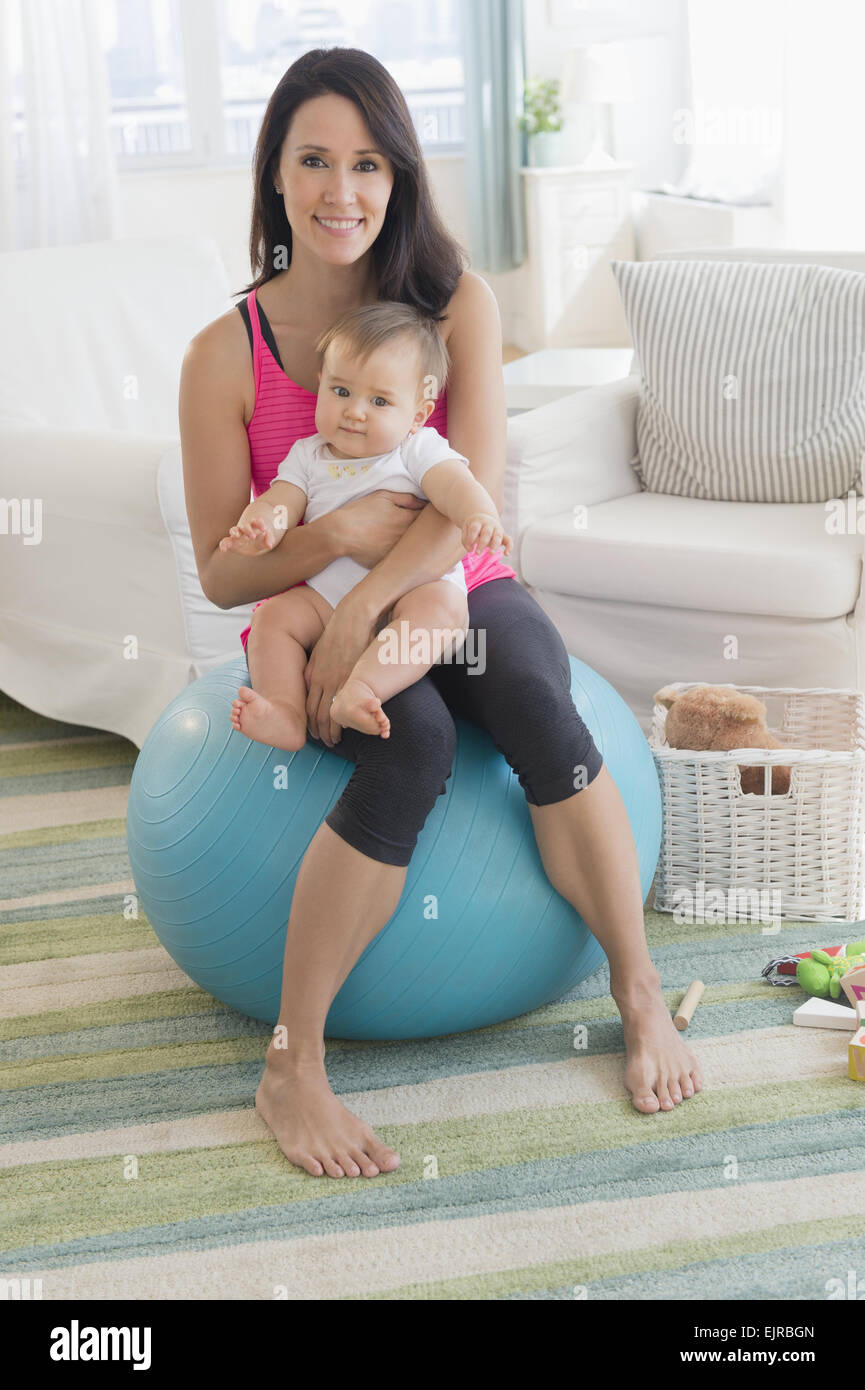 Mixed race mother holding baby on fitness ball Stock Photo