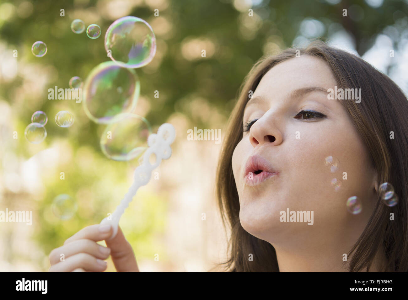 Close up of Caucasian woman blowing bubbles outdoors Stock Photo