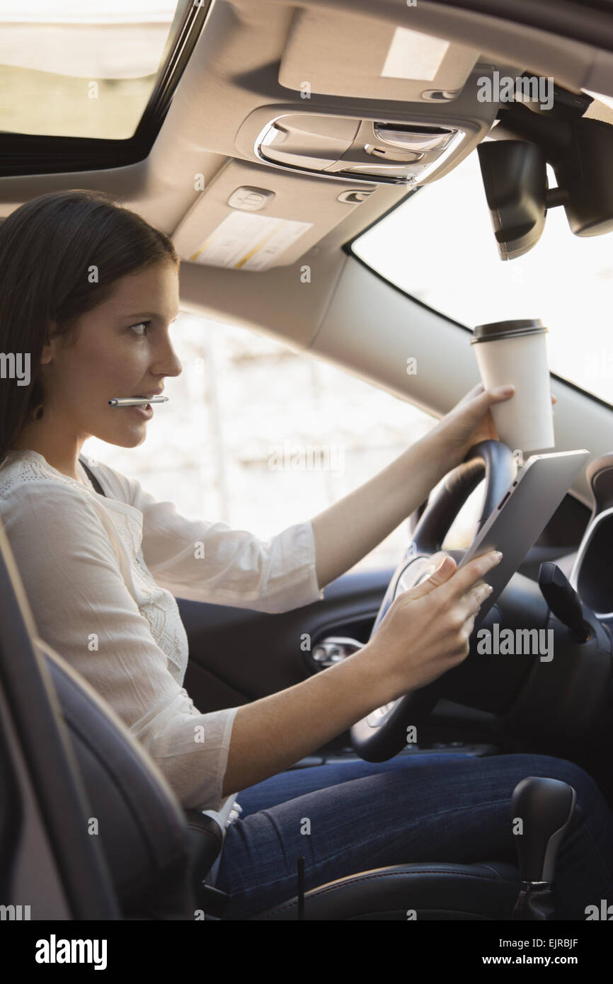 Caucasian woman multi-tasking while driving car Stock Photo