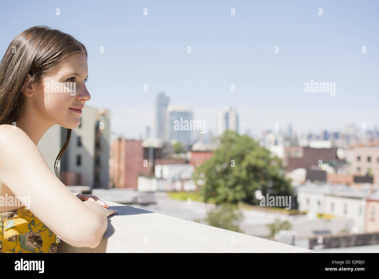 Caucasian woman overlooking cityscape from urban rooftop Stock Photo